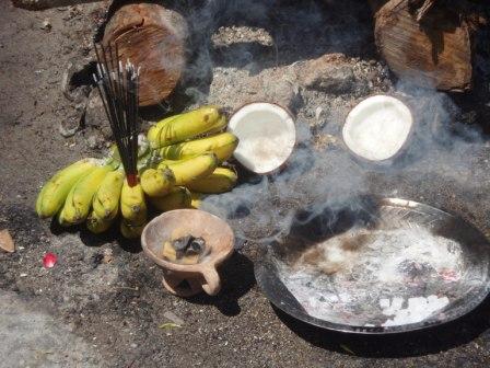 A bunch of bananas, a coconut split in two, an urn bearing burning camphor and a stainless steel dish bearing holy ash and camphor